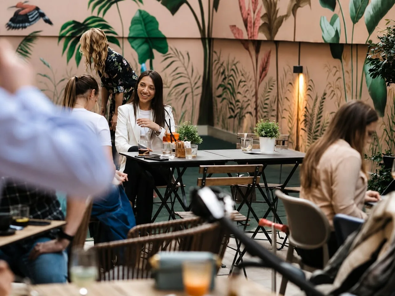 Bašta MoMo Bar & Play prostora sa stolovima, gostima i muralom